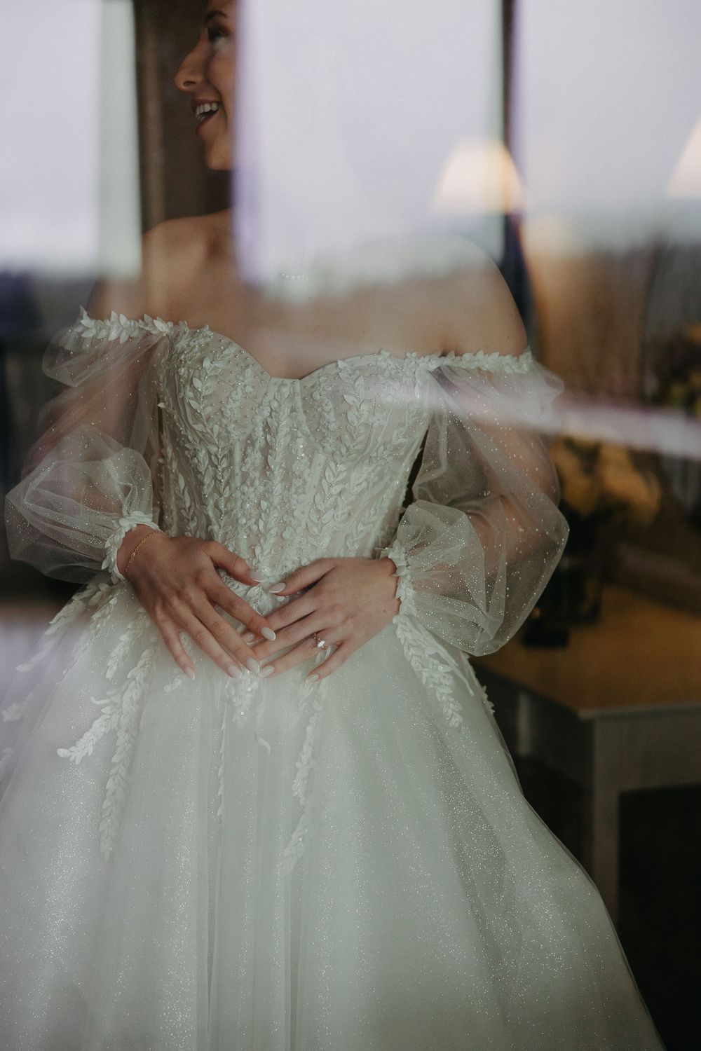 Close-up detail of intricate wedding dress bodice and puffy tulle sleeves.
