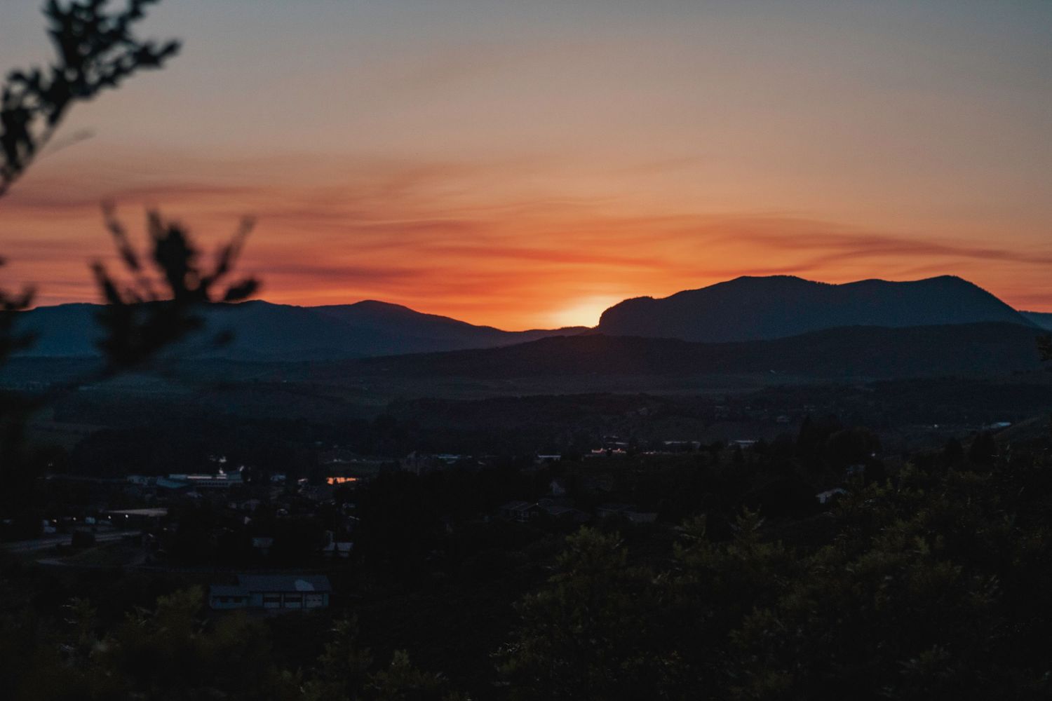 Dramatic sunset silhouettes mountains against an orange and purple sky.