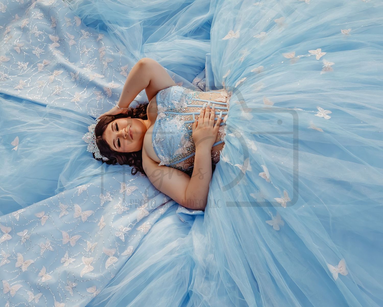 A flowing light blue ballgown with intricate details spreads across the ground in a dreamy pose.