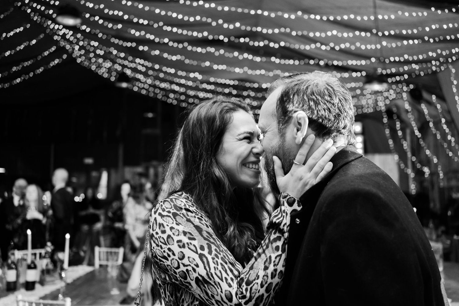 A couple shares their first dance under a tent with twinkling lights at their wedding reception.