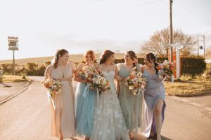 Bridal party in pastel dresses poses together at sunset.
