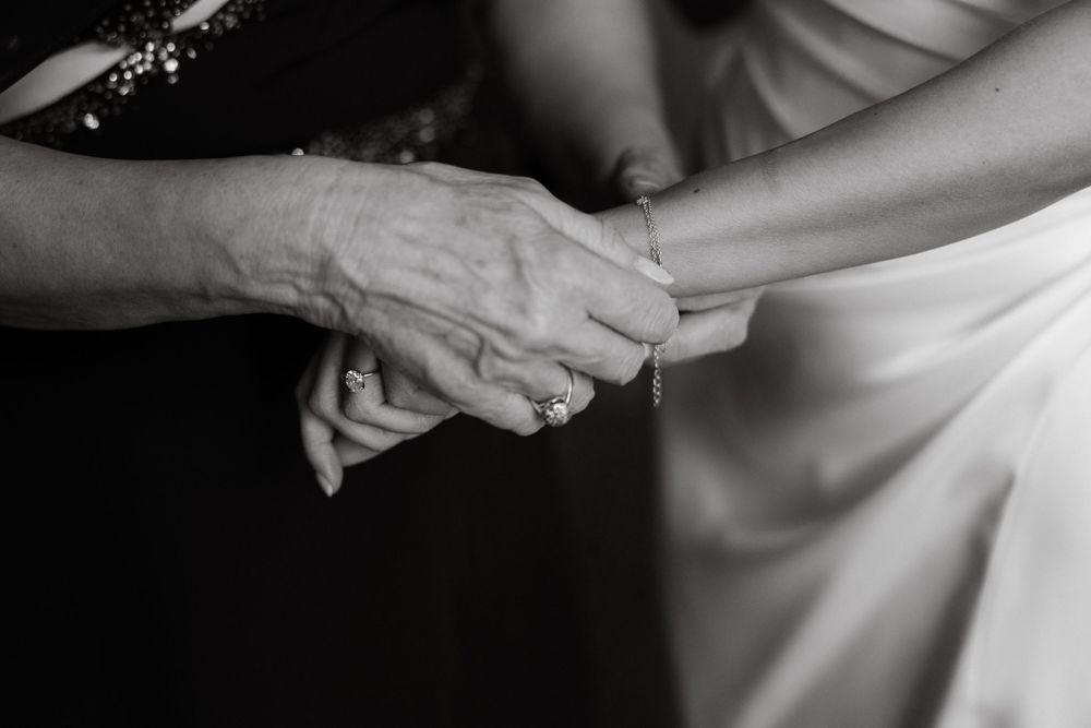 Black and white detail shots of hands delicately adjusting formal wedding attire.