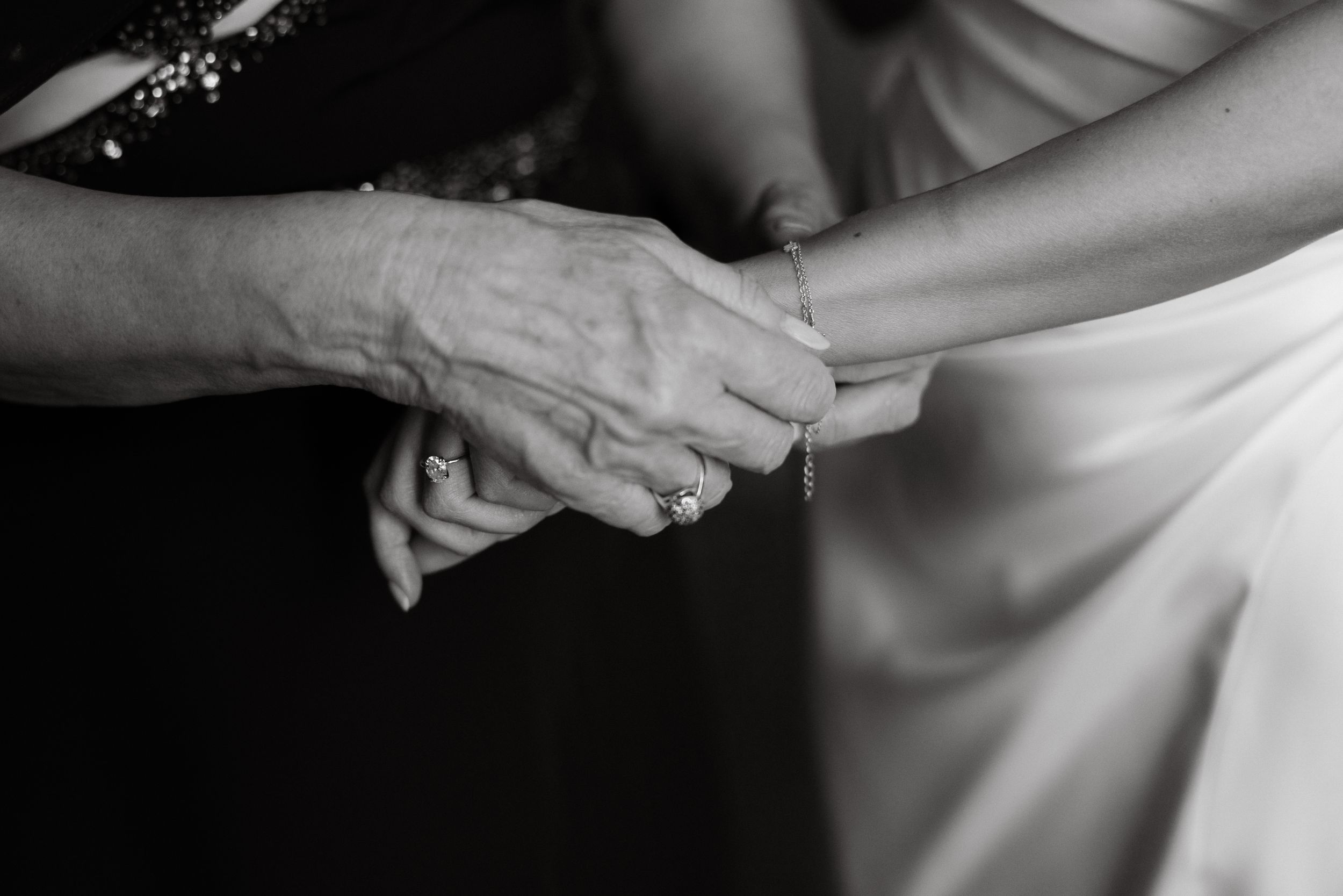 Black and white detail shots of hands delicately adjusting formal wedding attire.