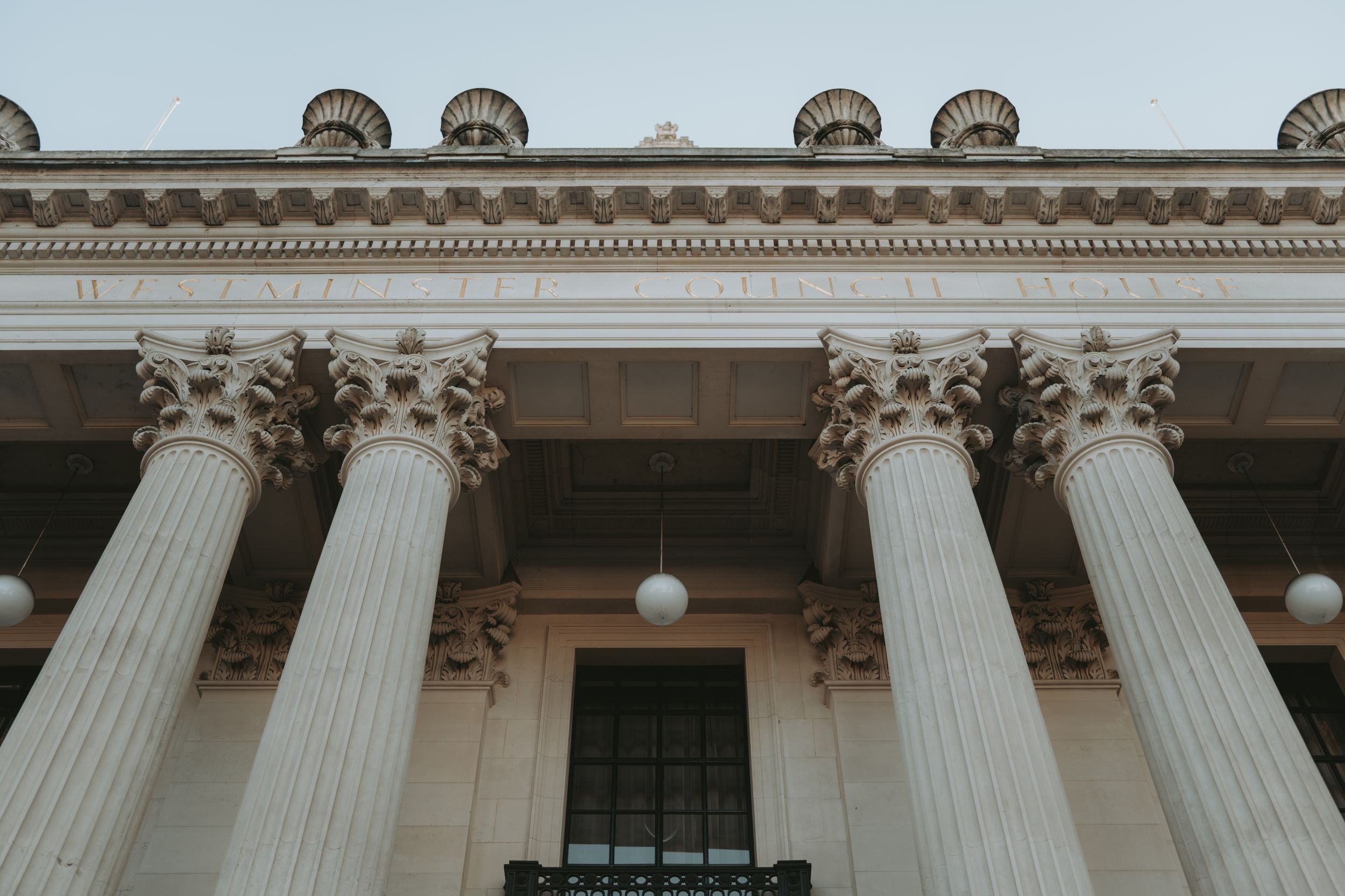 Architectural detail of white classical columns and ornate cornice on a grand historic building facade.