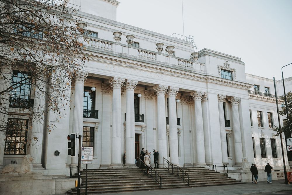 Panoramic view of a grand white neoclassical building with columns and steps.