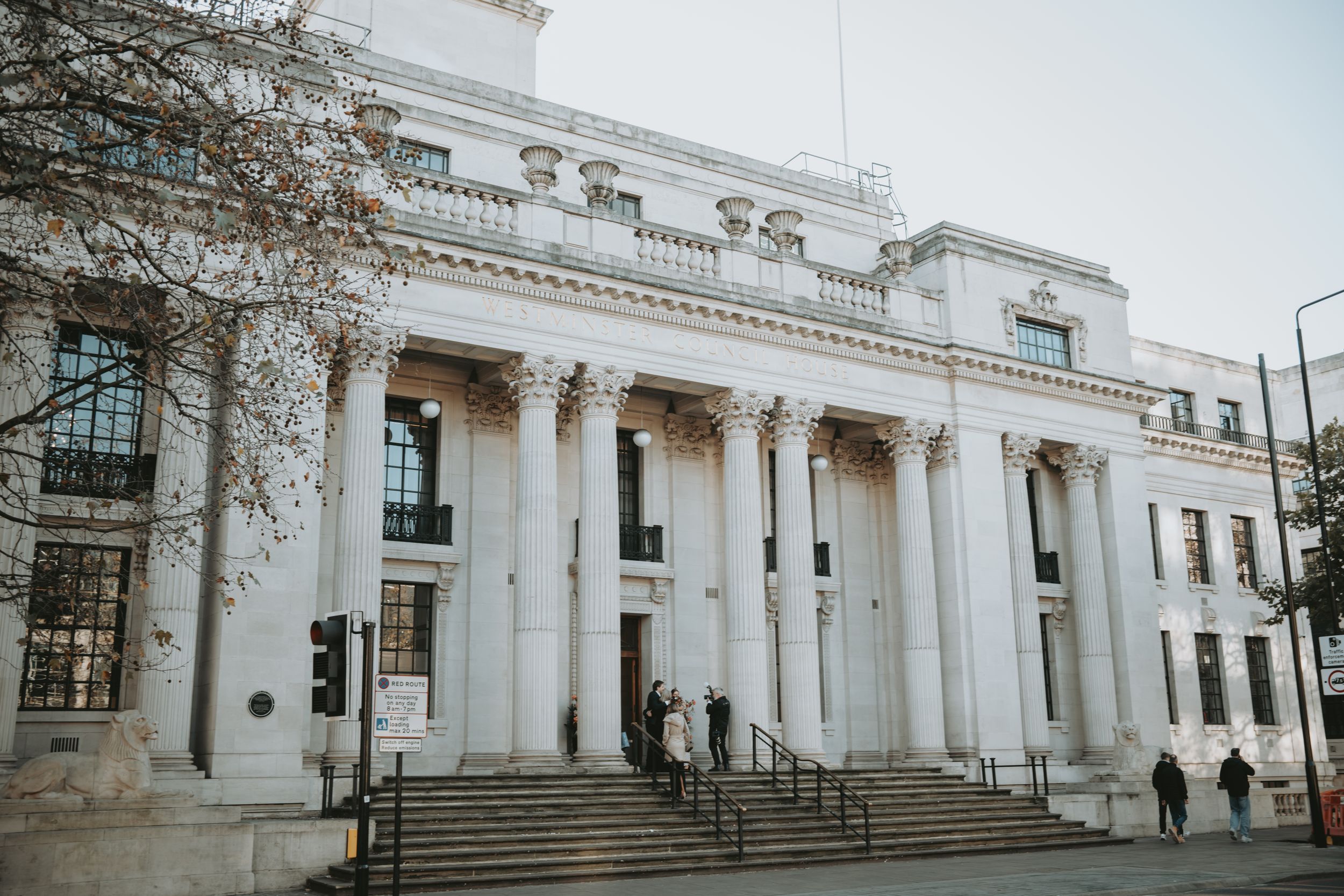 Panoramic view of a grand white neoclassical building with columns and steps.