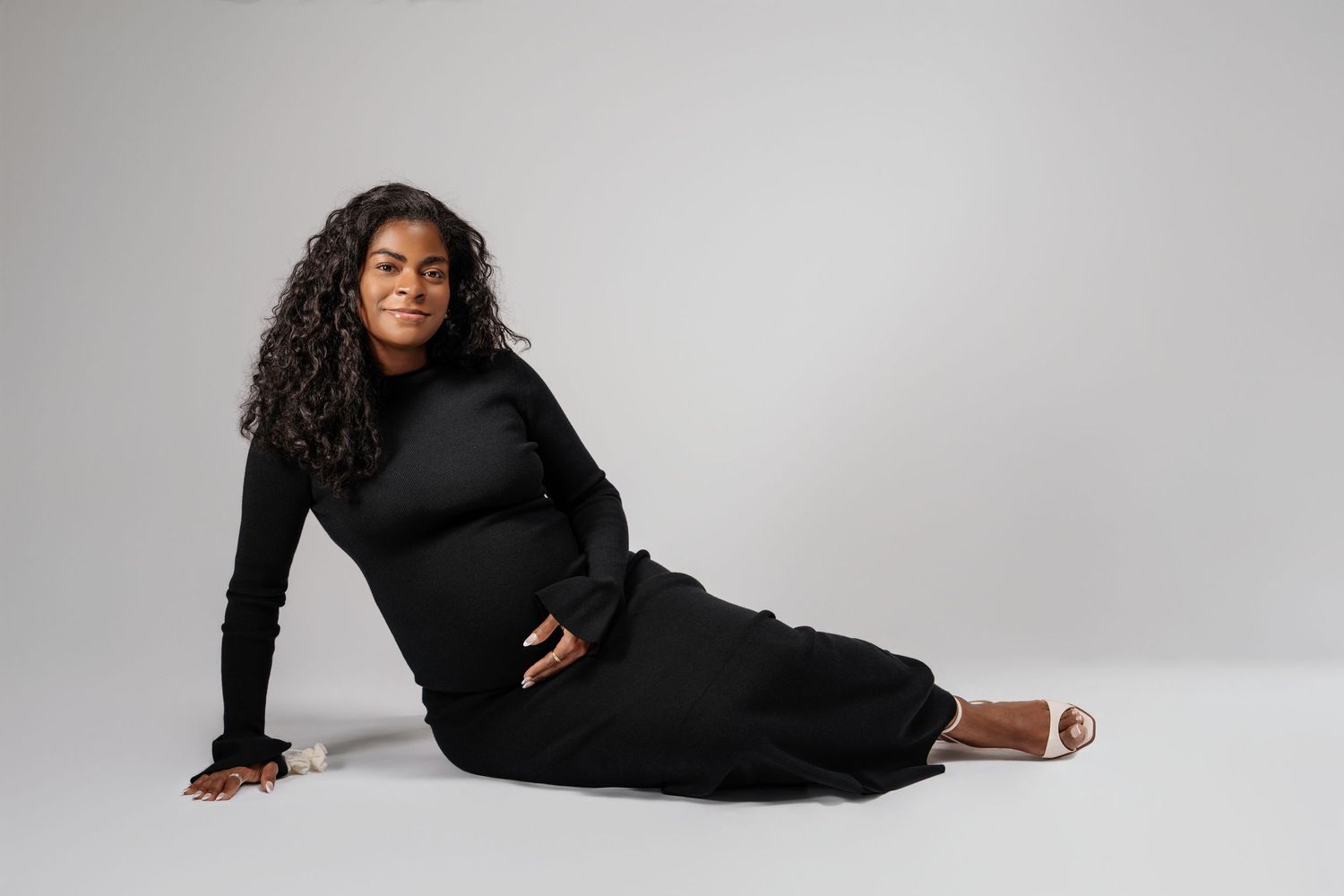A person in a black dress poses gracefully in a series of artistic positions against a white studio backdrop.