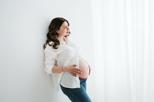 Clean minimalist maternity portraits against white backdrop showing pregnancy joy.