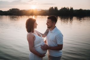 Romantic sunset maternity photos by lakeside with warm golden light.