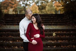 Fall maternity photos on rustic steps surrounded by autumn leaves.