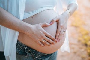 Close-up shots of hands tenderly touching a pregnant belly in natural lighting.