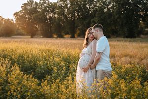 Golden hour maternity photos in blooming wildflower field at sunset.