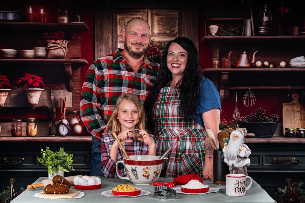 A family poses together in a festive kitchen with matching plaid outfits and holiday decorations.