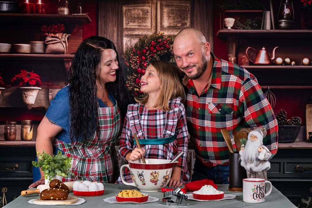 Three people share a joyful moment while baking together in a rustic kitchen setting.