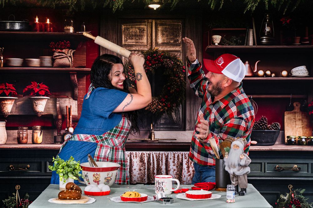 Two people high-five while cooking in a kitchen with holiday decorations.