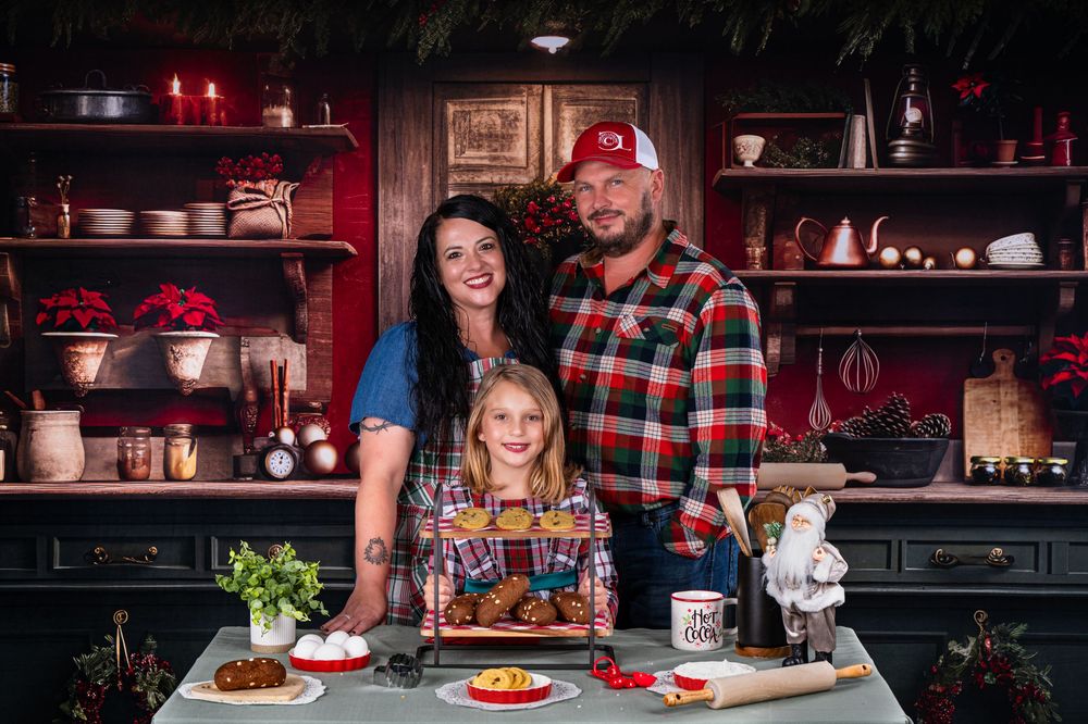 A family poses together at their kitchen counter with holiday decorations and treats.
