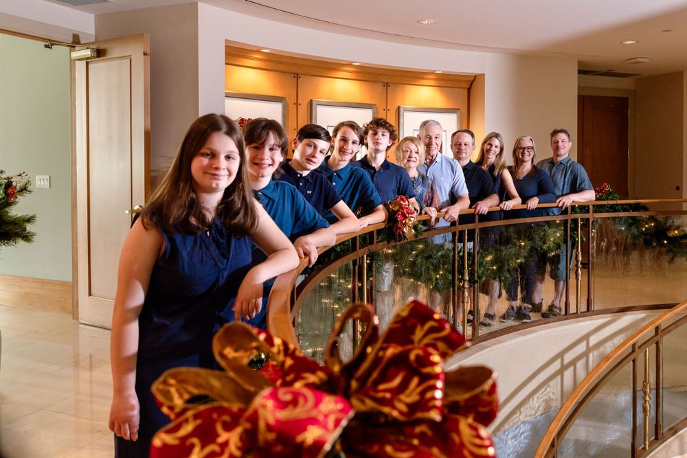 Family group posing on an elegant staircase wearing coordinated navy blue and white outfits.