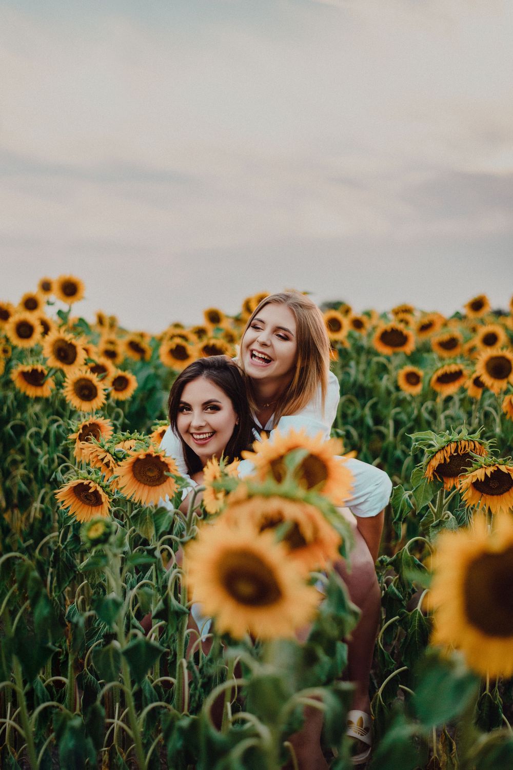 Joyful summer photoshoot in a field of blooming sunflowers at sunset.