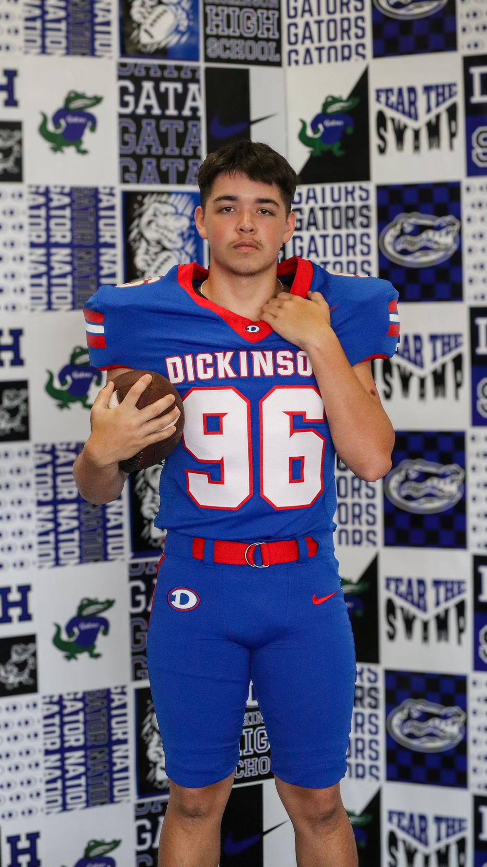 Athletes in blue Dickinson uniforms posing against team logo backdrop.