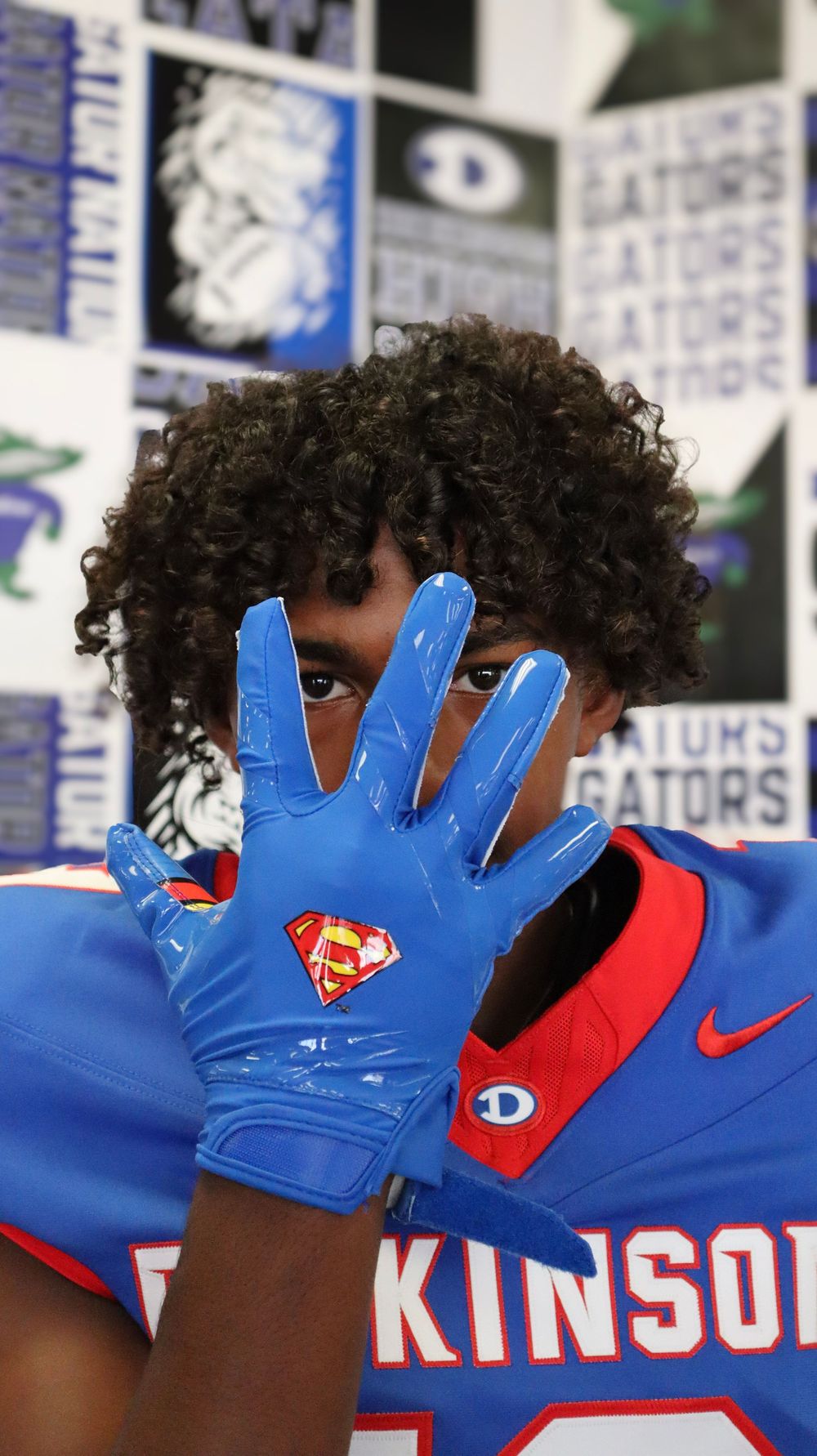 Close-up of blue Nike football gloves with Superman logo detail.