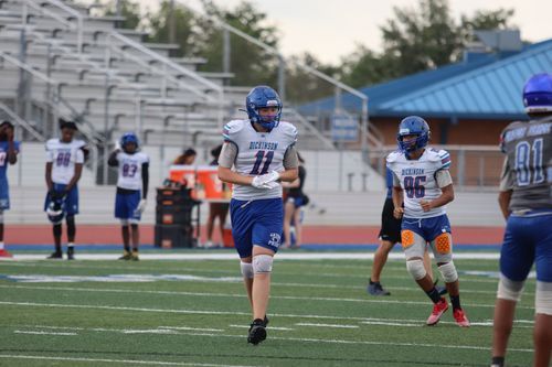 Football player in blue and white uniform runs drills during practice on field.