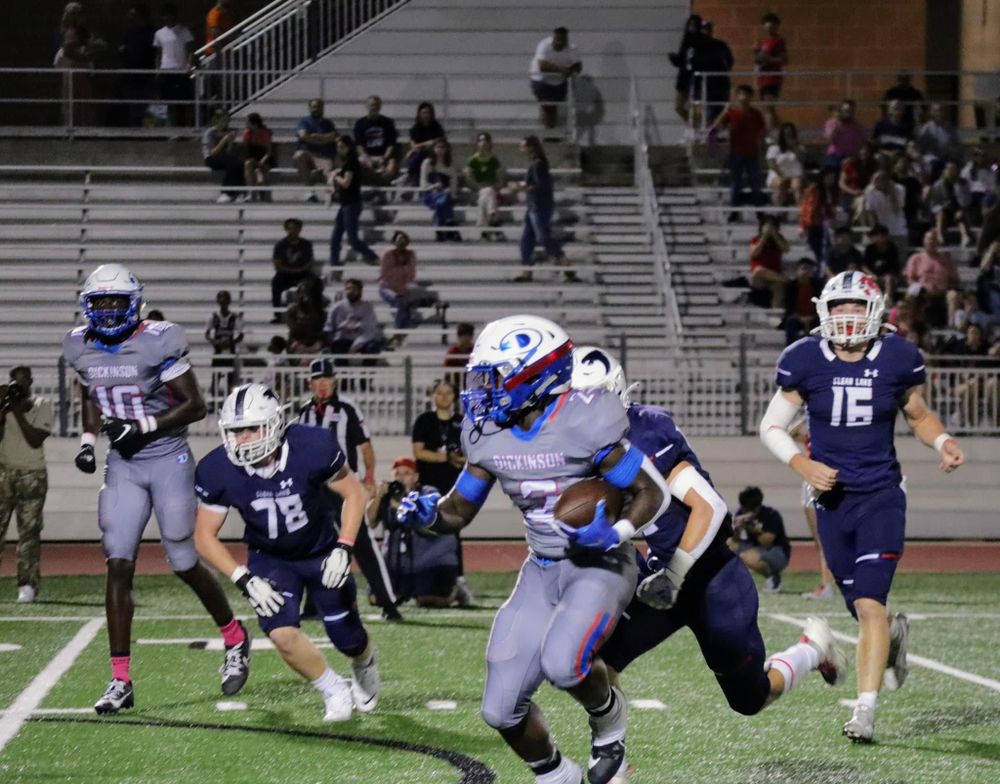 Football players from opposing teams collide during an intense play on the field.