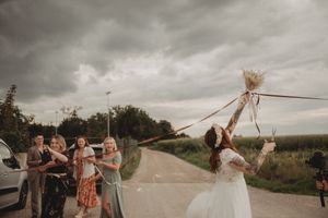 Wedding celebration on a country road with group watching someone reach for hanging decorations.