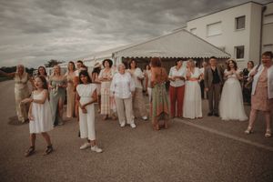 Wedding party guests lined up outdoors wearing coordinated neutral-toned outfits.