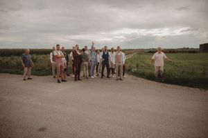 Wedding guests gathered on a country road against a dramatic cloudy sky.