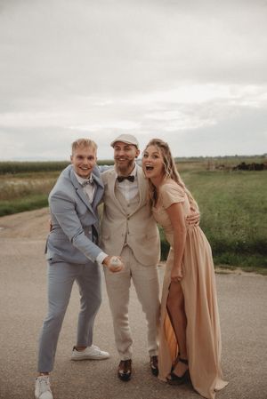 Wedding party members pose playfully on a countryside road in formal attire.