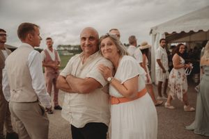 Wedding celebration guests enjoying candid moments under a white tent.