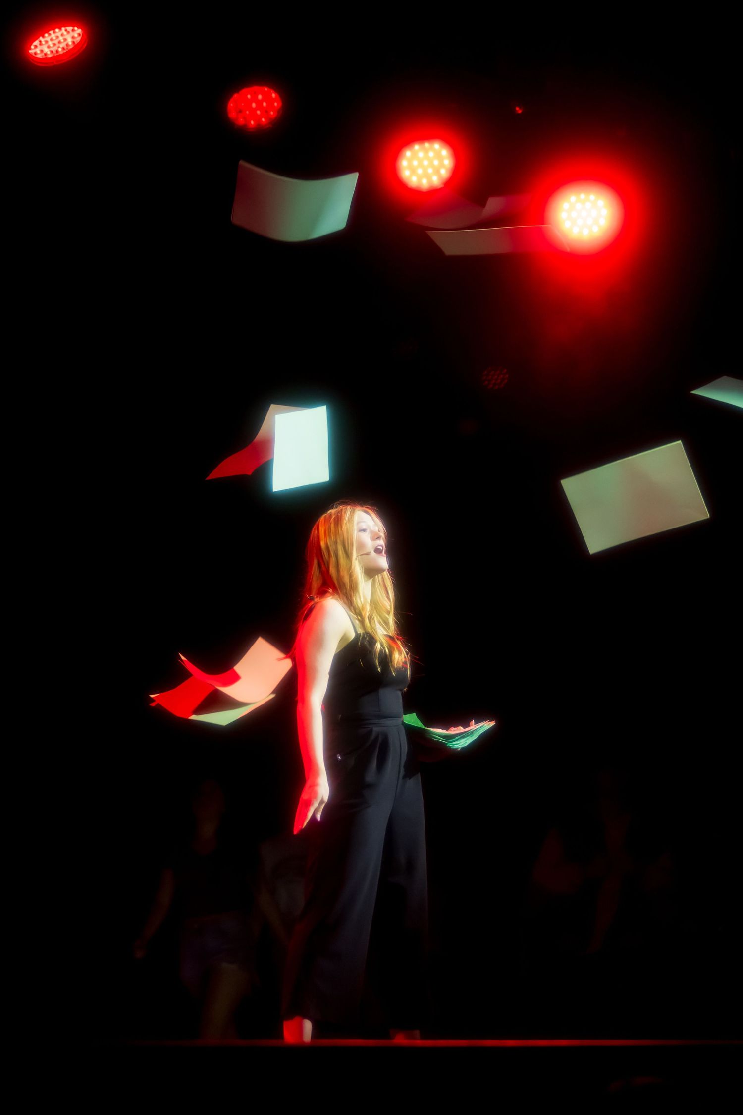 Dramatic red stage lighting creates moody atmosphere during performance.