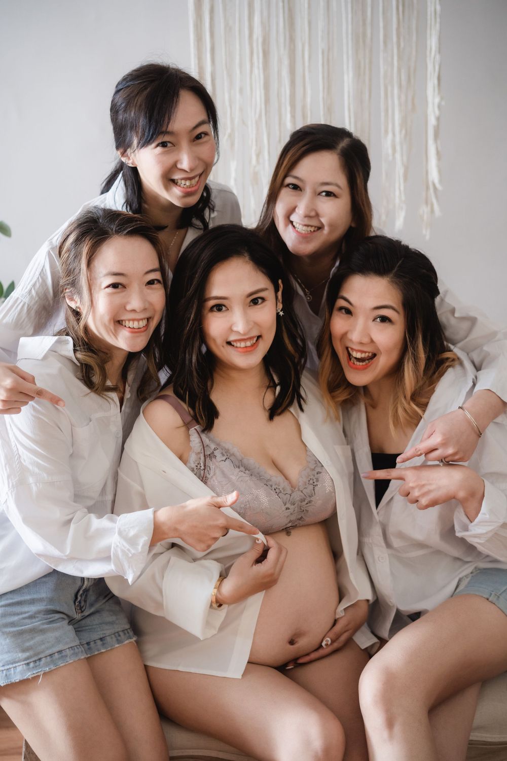 Group of women in white shirts celebrating with pregnant friend.