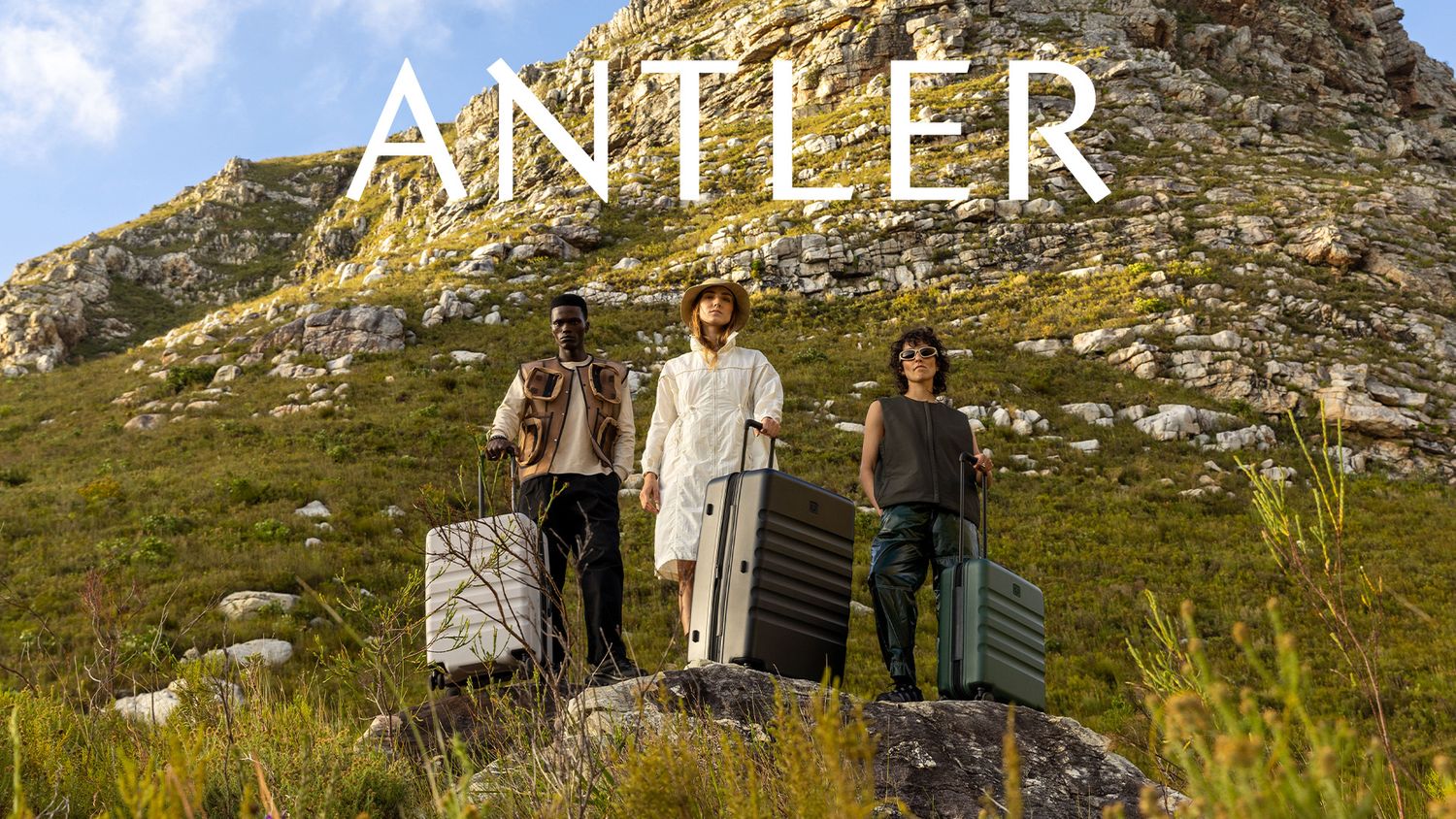 Models pose in front of green mountainside landscape outside Cape Town for a campaign photo production for suitcase brand Antler.