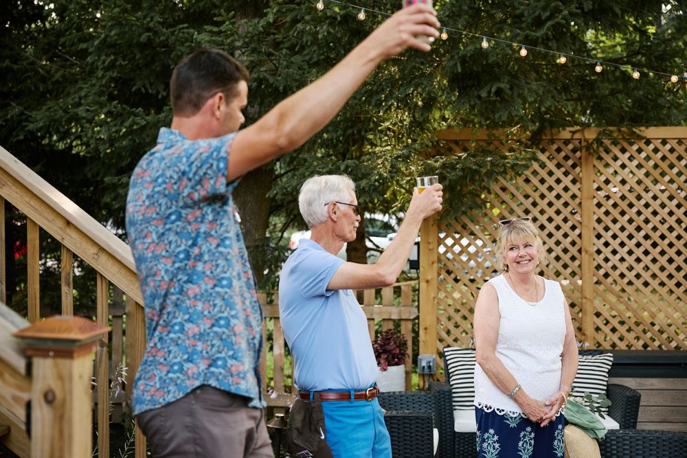 People dancing together outdoors in a line formation with lattice fencing visible in the background.