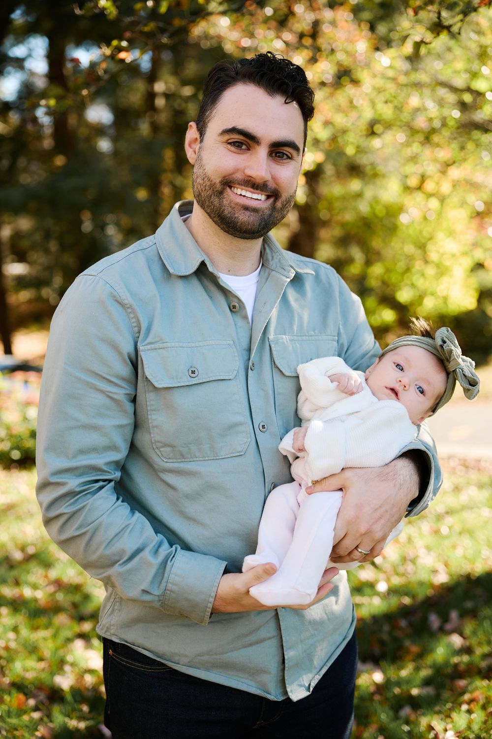 A series of outdoor photos showing a person in a light blue jacket holding a small baby against an autumn background.