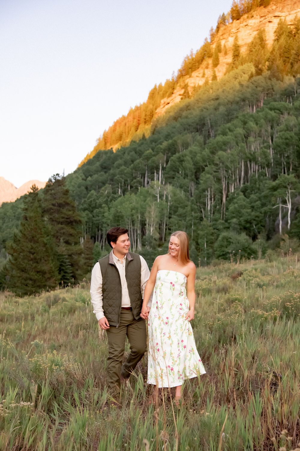 A couple shares tender moments while walking through a mountainside meadow at sunset in Vail Colorado.