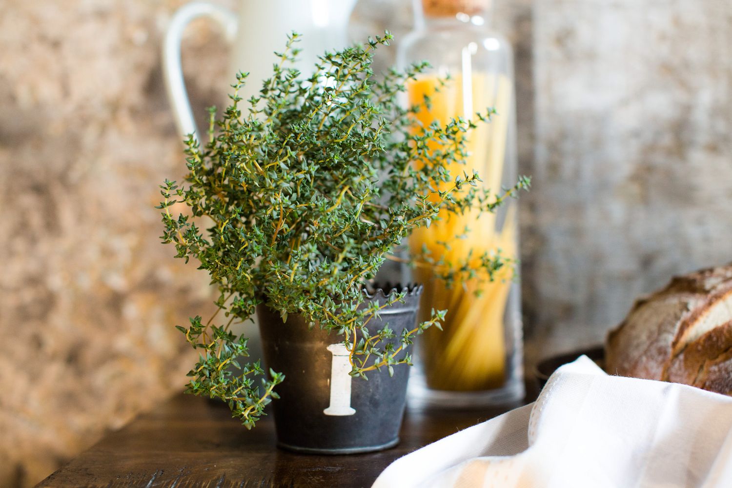 Industrial-chic wedding reception space with ghost chairs, greenery centerpieces, and large number 3 on concrete wall.