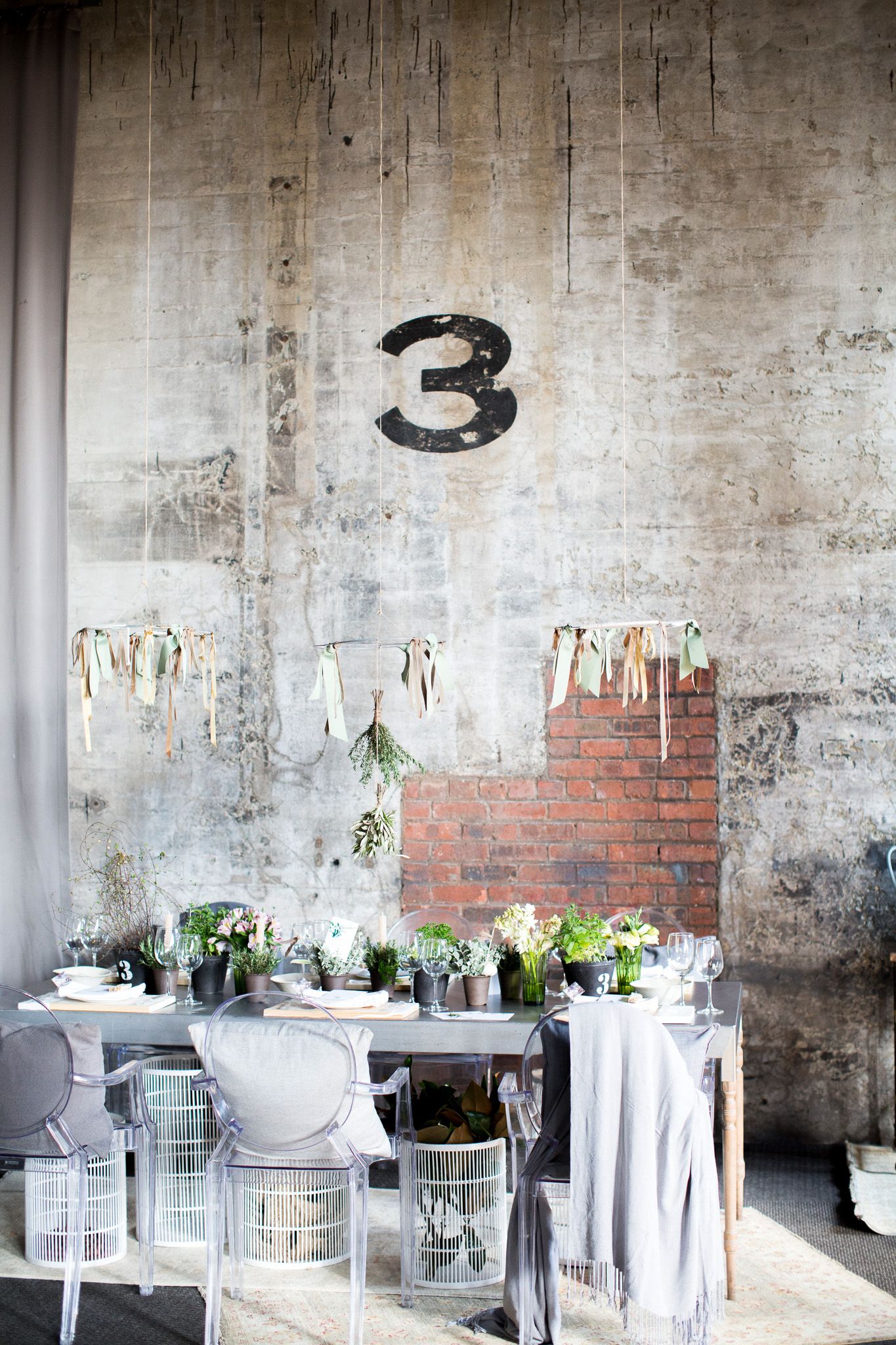 Neatly folded linen napkin on a wooden place setting with wine glasses and greenery in soft bokeh background.