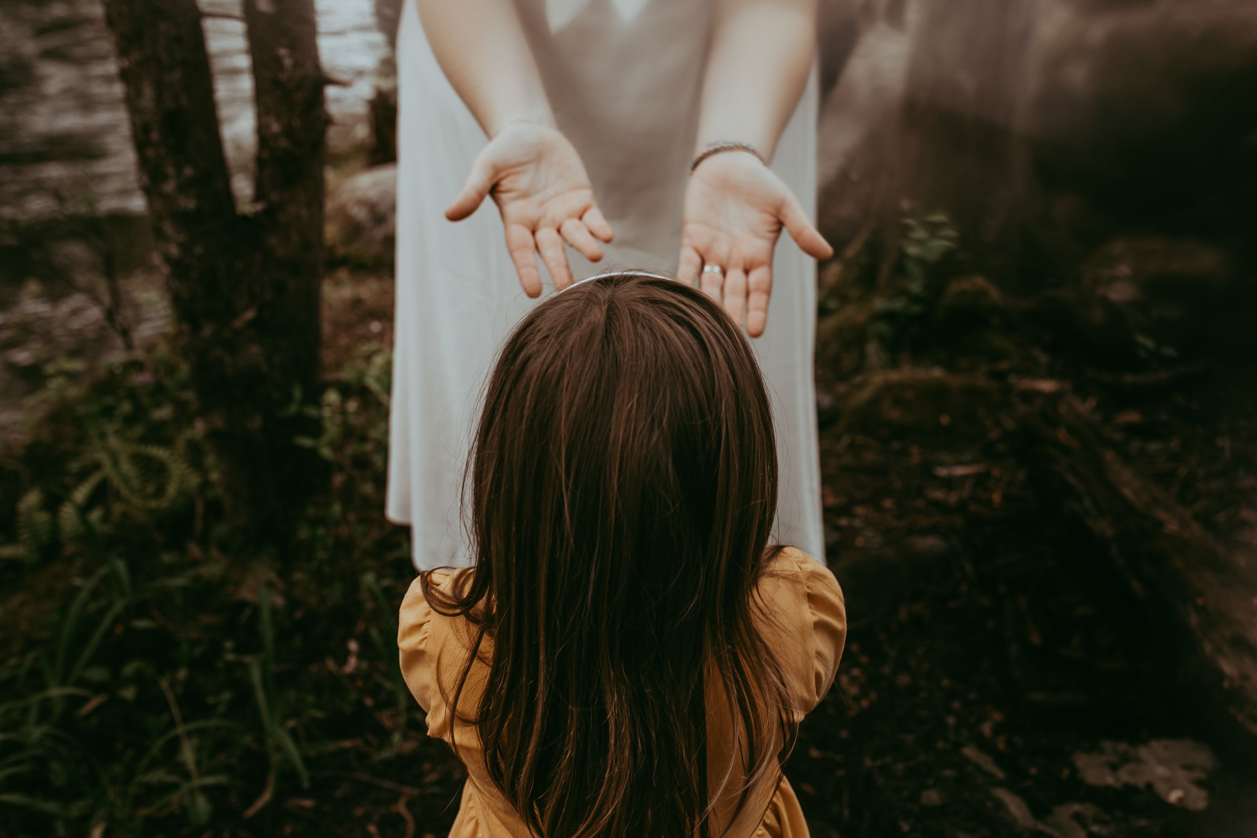 A mother holds out her hands to her daughter in a dark forest. Whitney Popp, Phoenix Arizona photographer.