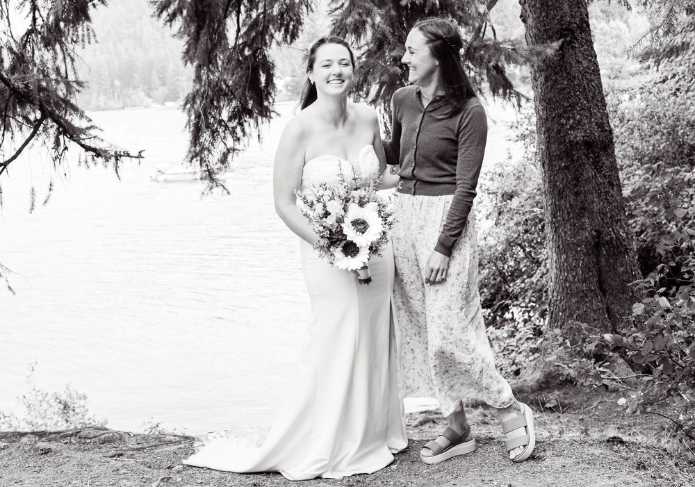A romantic black and white wedding image showing a couple embracing outdoors among trees.