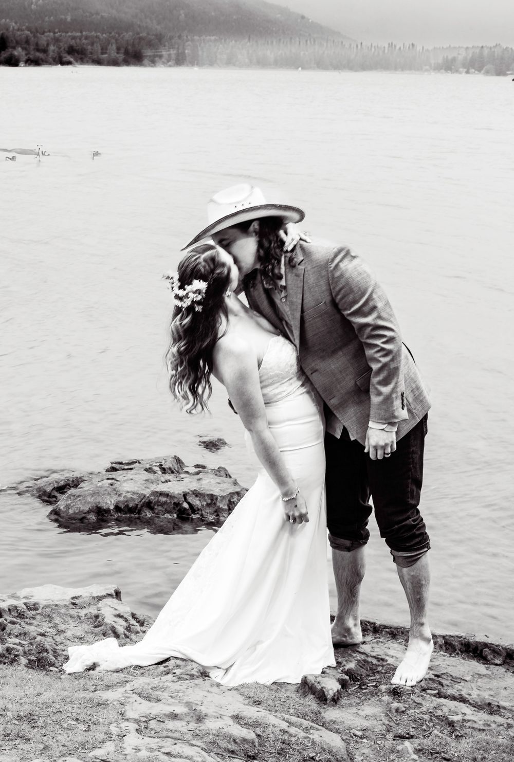 A romantic photo sequence shows a couple on a beach bending down together to draw in the sand beside a lake.