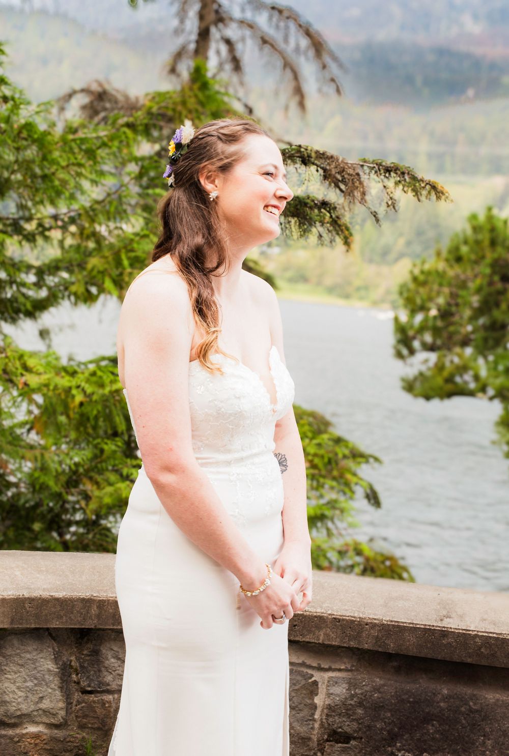 A wedding photo series shows a bride in a white dress standing by a stone wall overlooking a scenic mountain lake.
