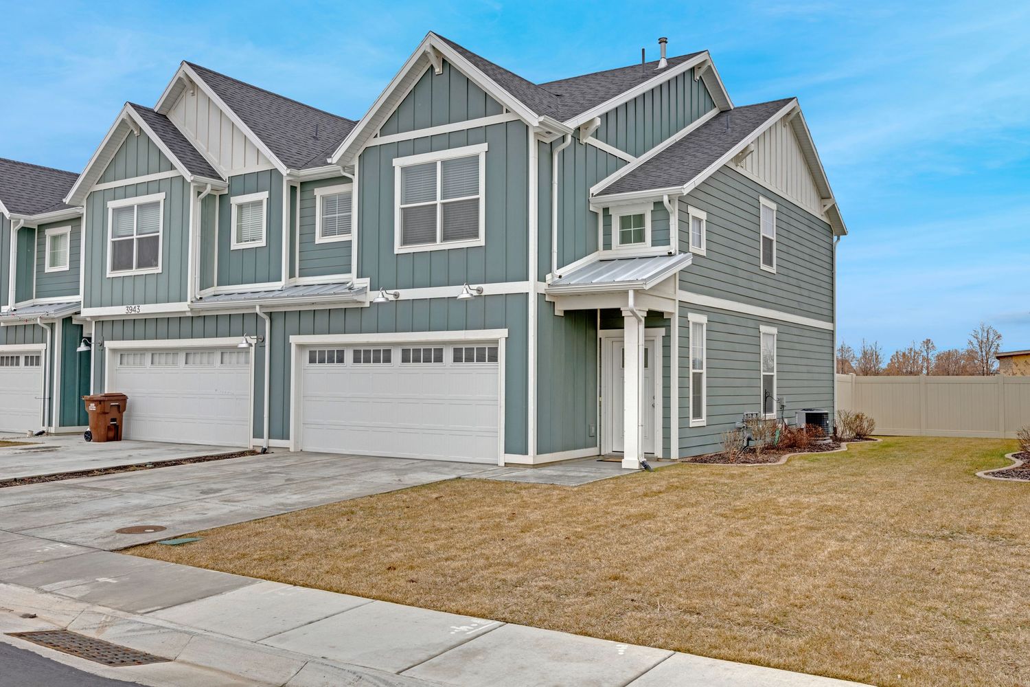 Modern gray craftsman-style townhome with two-car garage, board and batten siding, and covered entry porch.
