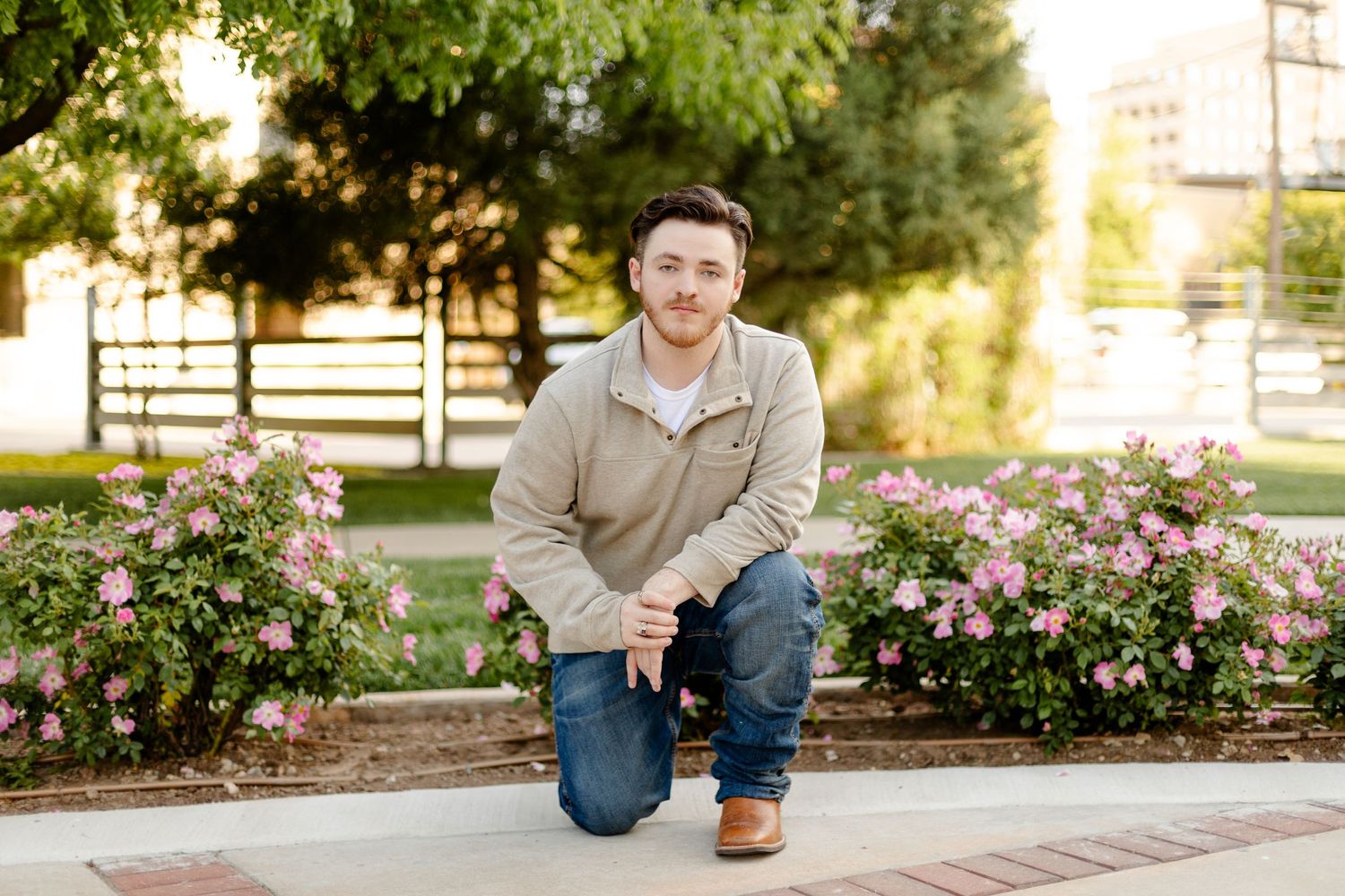 Portrait in a garden setting with pink roses and brick walkway.