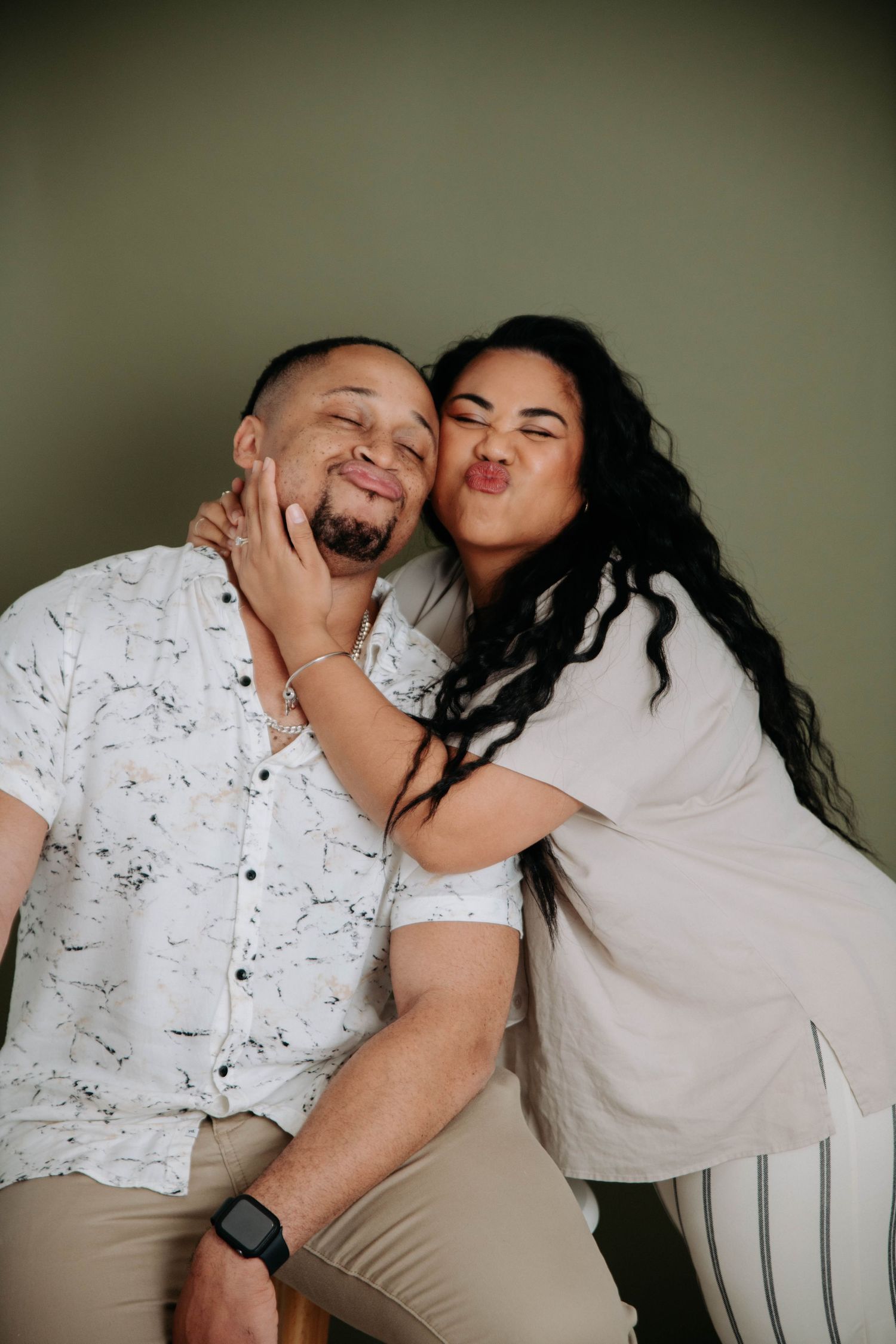 Two people share a playful moment together against a studio backdrop.