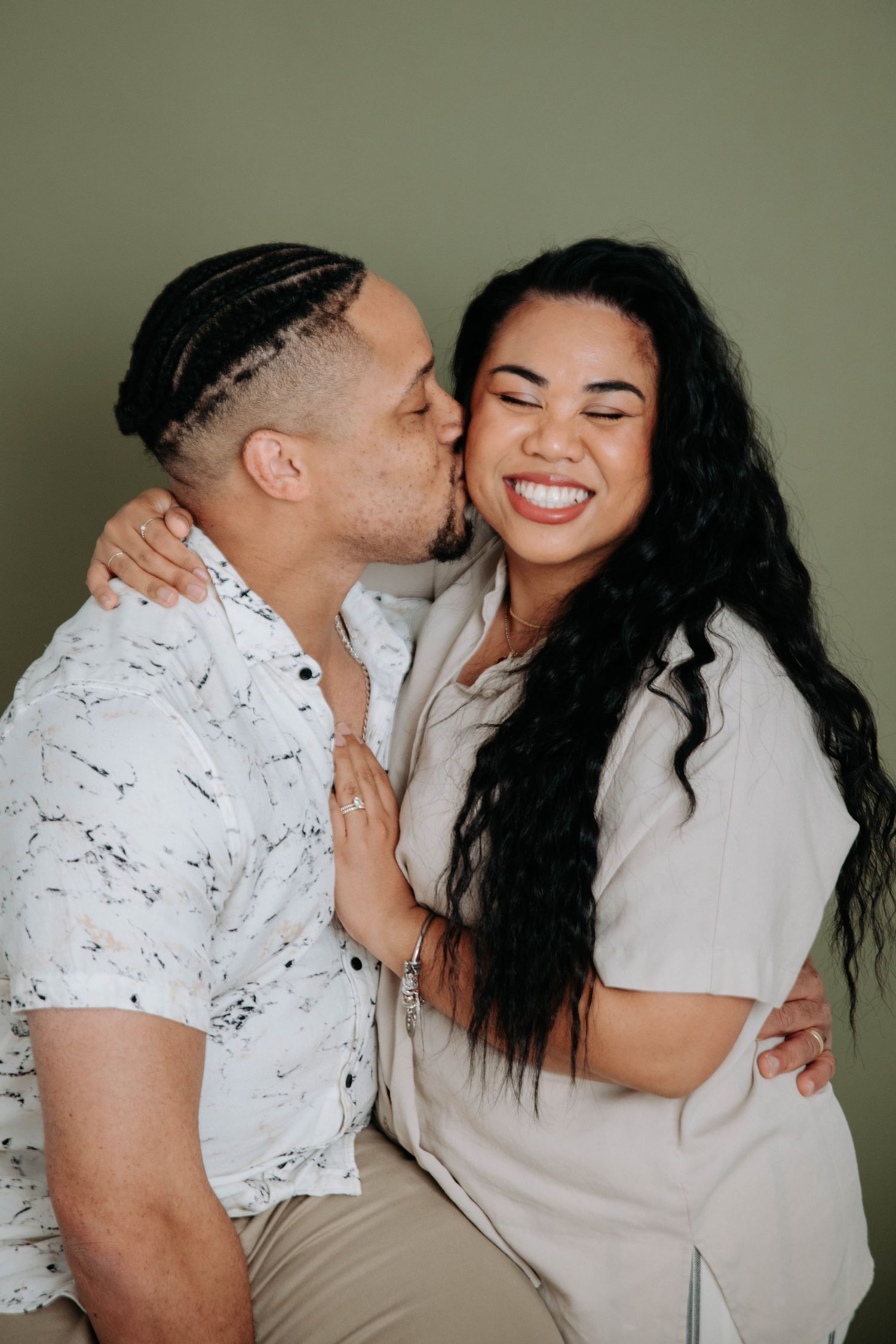 A joyful couple sharing an intimate moment against a green backdrop.