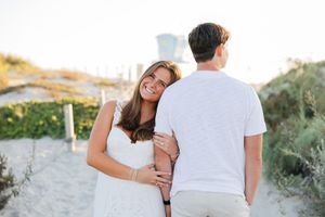 A couple embraces and laughs together during an outdoor photoshoot in a scenic mountain landscape.