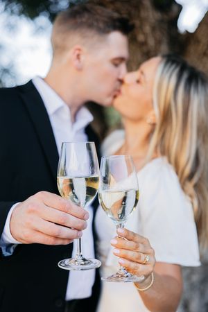 Romantic wedding couple toasting with champagne glasses during their celebration ceremony outdoors.