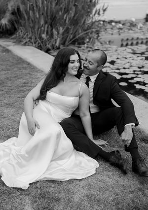 A romantic black and white photo series showing a couple laying on grass together in wedding attire.